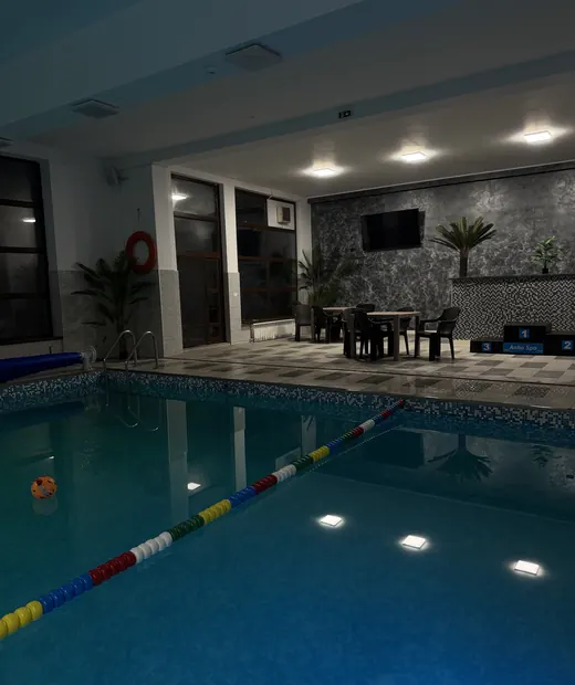 Mese și scaune lângă piscină, cu un televizor pe perete