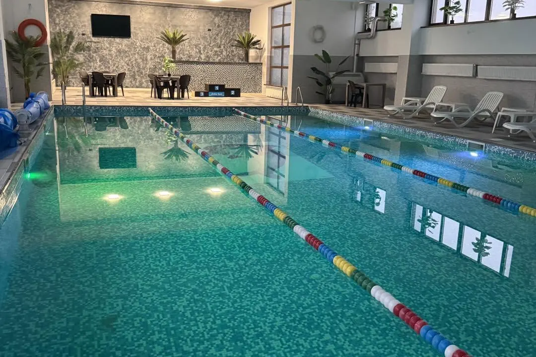 Piscina cu luminile verzi din apă și zona de relaxare din spate